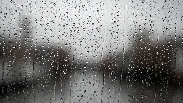 Raindrops clinging to a window pane create a moody, atmospheric scene ideal for adding a touch of reflective beauty or a calming, rainy day background