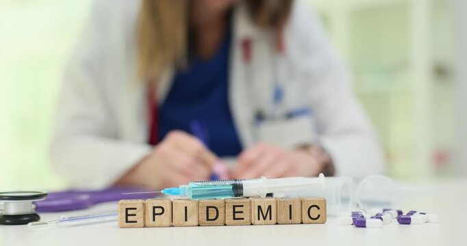 Wooden blocks spell word Epidemic near syringes put on top on desk. Infection specialist prepares vaccine batch logging epidemic data carefully