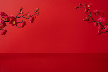 Side view of a red Chinese New Year backdrop with pink blossoms on dark branches, conveying festive...