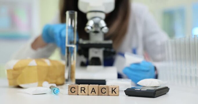 Wooden blocks spell word Crack on lab table near scale devices. Laboratory scientist tests crack sample while preparing toxicology report at workplace