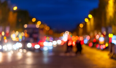 Fototapeta premium Boulevard in the French capital at dusk or blue hour. Rush hour with traffic jam on the Champs-Elysées at night. Busy main street in Paris with many blurred colorful lights from passing cars. 