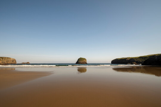 Sandy beach and small island in the Western Coast of Asturias, Spain