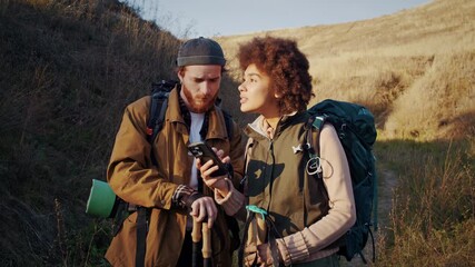 Portrait of young tourists couple discusses route navigating with smartphone - Powered by Adobe