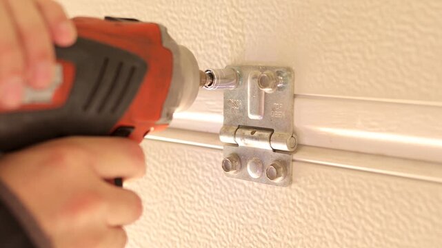 Close-up of impact driver securing garage door hinge screws