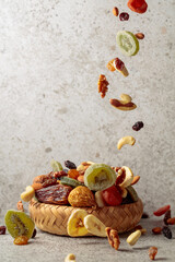 Mix of dried fruits and nuts in motion on a gray background.