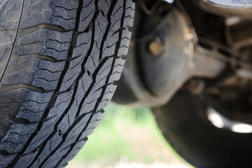 Closeup of a four-wheel drive pickup truck all-terrain tire showing worn tread patterns, dirt, and signs of rugged off-road use