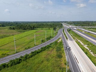 Drone shot a large highway interchange crossing over green farmlands in Thailand