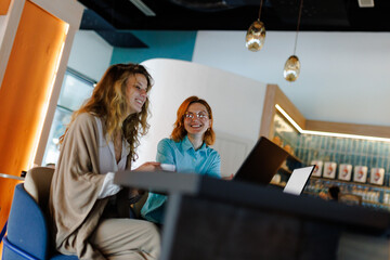 Businesswomen collaborate in modern workspace, engaging with technology and ideas during a productive meeting in a stylish cafe
