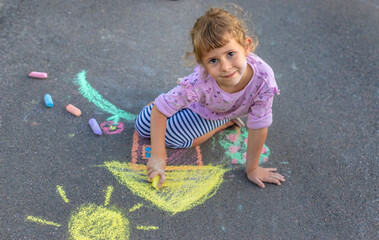 Naklejka premium Children drawing with chalk on the asphalt. Selective focus.