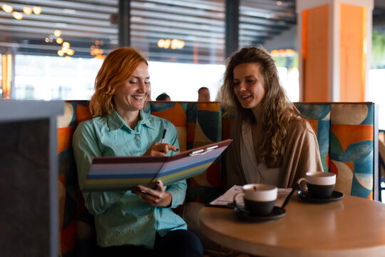 Businesswomen collaborating at a modern cafe, discussing ideas while enjoying coffee in a vibrant workspace