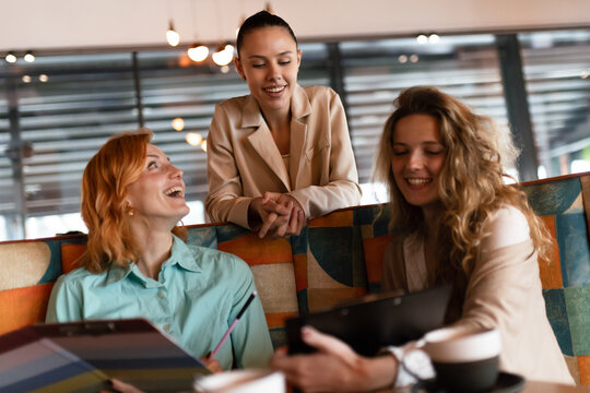 Businesswomen collaborating in a modern workspace, sharing ideas and discussing projects during a team meeting in an urban cafe environment
