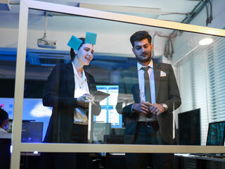 Diverse business professionals collaborating on a strategic project on glass board for brainstorming and data visualization. Digital transformation, corporate innovation, and successful problem solve