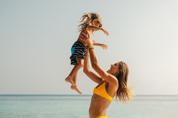 Mother and son playing on the beach during holiday