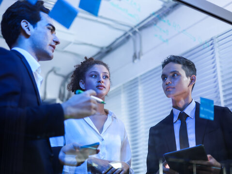 Team collaborating on a challenging business strategy, analyzing data, and brainstorming future innovations. Forward thinking corporate success and digital transformation. Group meeting at the office