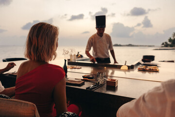 Teppanyaki dining experience at sunset with chef and patrons by the ocean