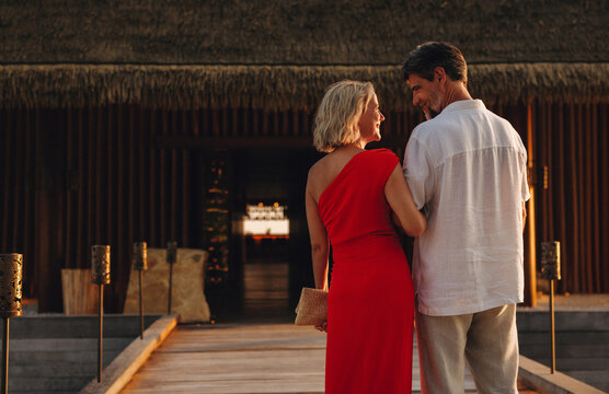 Romantic couple walking to luxury resort restaurant at sunset on honeymoon