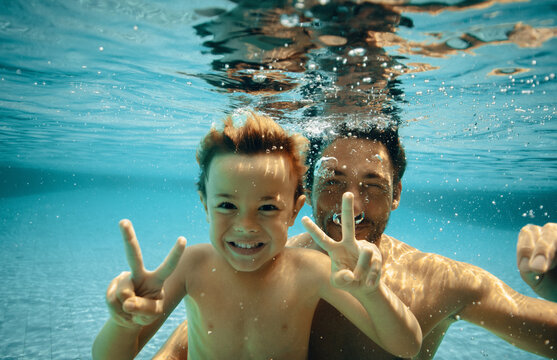 Father and son posing underwater with peace signs