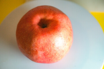 The apple on the white plate is cut in half with a knife
