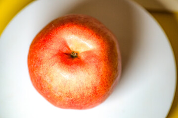 The apple on the white plate is cut in half with a knife