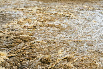 Smudged water flows profusely. River water flowing profusely. Flood waters rushing down river after storm flows through. Turbulent river dam. Water turbulence of river due to dam. Water Nature Texture
