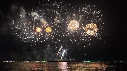 A spectacular fireworks display fills the night sky above water celebrating Christmas or New Year 