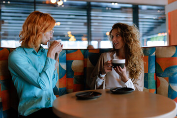 Businesswomen engage in a productive discussion over coffee at a modern cafe during the late morning hours on a busy weekday