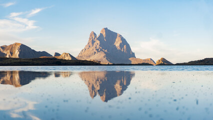 Mountain reflection in a calm lake under a clear sky with other mountains in the background view