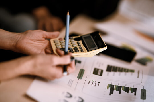 People work on financial calculations with a calculator and documents in a modern office setting during the day