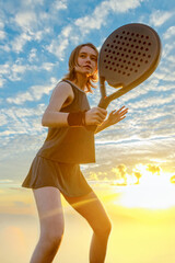 Padel junior tennis player with racket. Girl teenager athlete with paddle racket on court outdoors. Sport concept. Download a high quality photo for the design of a sports app or web site.