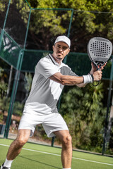 Padel player on the padel court with padel racket and ball in action. Open social tour template. Padel tennis player outdoors. Paddle tenis template for design ads with copy space.