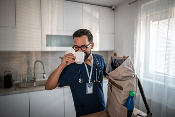 Healthcare worker drinking coffee preparing for work in kitchen