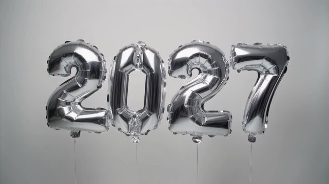 Silver &ldquo;2027&rdquo; balloons on strings against light gray background symbolizing milestone celebration and elegant simplicity
