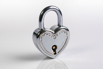 Silver heart shaped padlock on reflective white surface
