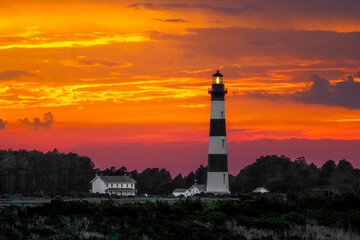 The historic Bodie Island Lighthouse, with its black and white stripes, is backed by a colorful sunset sky in Cape Hatteras National Seashore on the North Carolina Outer Banks.