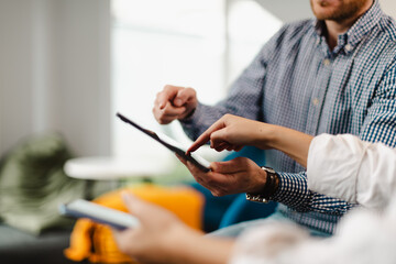 Business professionals collaborate over a digital device in a modern office setting while discussing strategies and sharing insights in an informal meeting
