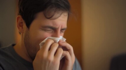 Bearded man grimacing from illness or allergies, anticipating a powerful sneeze. Quickly uses a clean white tissue to cover his nose and mouth, demonstrating proper hygiene and self-care.