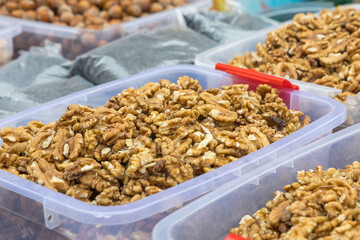 A detailed shot of a mound of shelled walnuts kernels placed in a clear plastic bin at a market or store