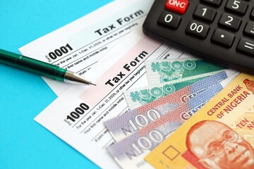Nigerian naira money bills and calculator with tax form close up. Taxation and accounting concept