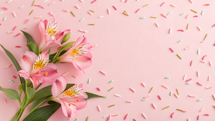 Colorful pink flowers arranged beautifully on a soft pink background with sprinkles scattered around