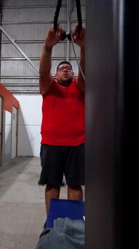 Video of a plus size man performing cable pull exercises at the gym. The scene captures strength, discipline, and determination during a real workout routine under artificial light.