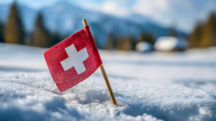 A small Swiss flag in fresh snow with a forest background, a national symbol of Switzerland, a winter vacation concept, a red fabric banner with white cross close-up.