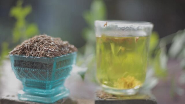 Black cumin seeds,shah jerra,Nigella sativa  and its extracted water in a transparent glass on brown wooden surface.