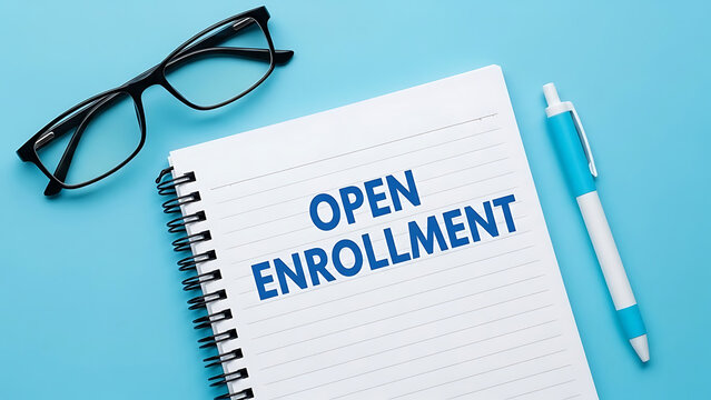 Open enrollment text on a notebook with glasses and pen