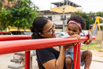 Obraz premium Young Latina Brazilian mother playing in the park with her black daughter. Rio de Janeiro, Brazil.