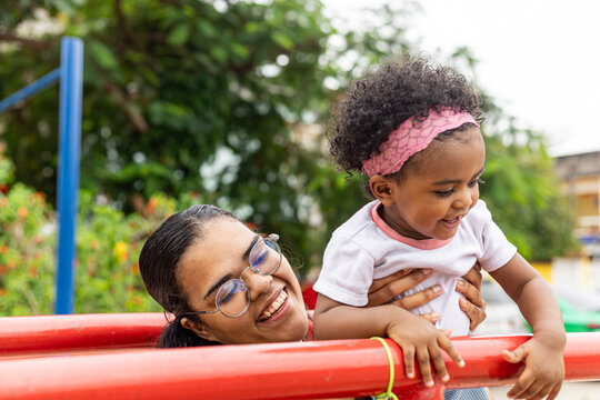 Young Latina Brazilian mother playing in the park with her black daughter. Rio de Janeiro, Brazil.