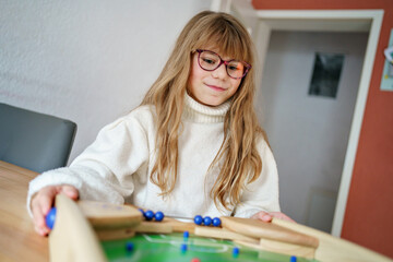 Little girl plays with teenager boy brother table football at home. Sibling having fun.