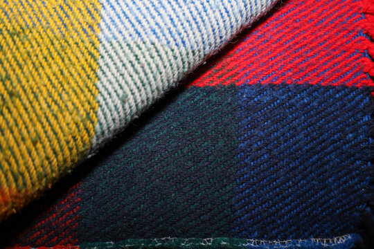 An abstract close-up shot showcasing the texture and tartan pattern of a thick wool throw blanket. - Powered by Adobe