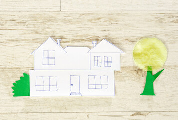 Simple paper house sketch with tree cutouts on light wooden background