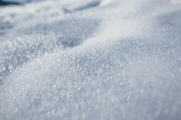 serene close-up of sparkling fresh snow, capturing delicate crystal textures illuminated by sunlight. Soft curves and gentle shadows create a peaceful winter atmosphere © alones