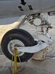 Close-up of a military aircraft's nose landing gear wheel and strut, resting on a concrete block...